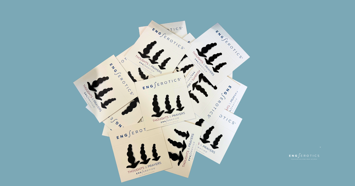 A pile of white cards with the text "ENG/erotics" and "Thoughts & Prayers" printed on them, featuring a black silhouette of three bulbous shapes, arranged on a teal background. The cards are stacked unevenly, with the brand name "ENG/erotics" visible on multiple cards.