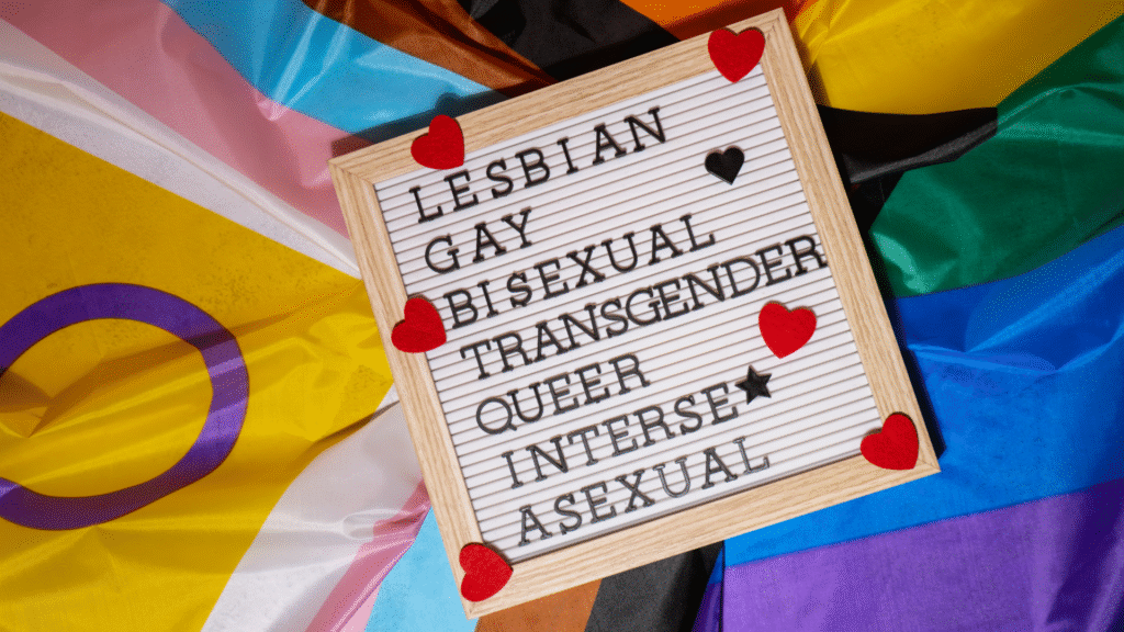 Letter board on Pride flags listing: Lesbian, Gay, Bisexual, Transgender, Queer, Intersex, Asexual, decorated with hearts.